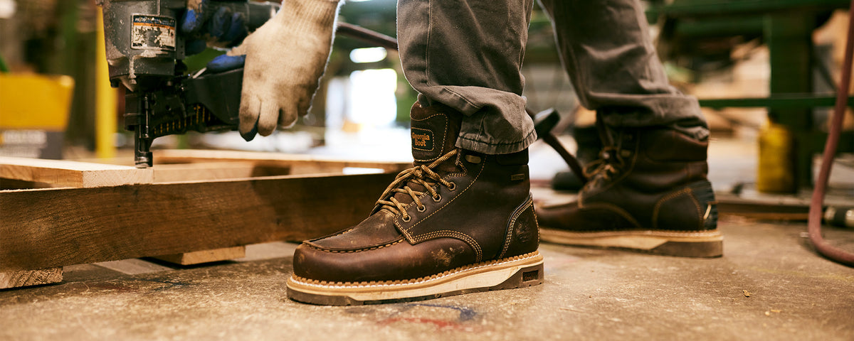 Person wearing brown work boots in a workshop setting
