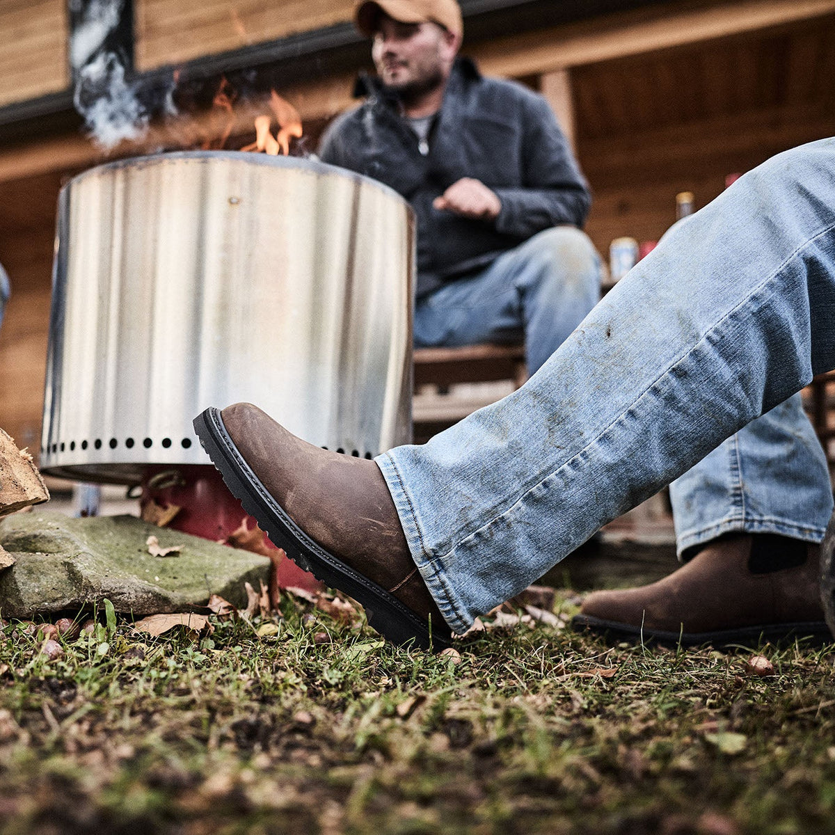 People sitting around a metal fire pit in an outdoor setting