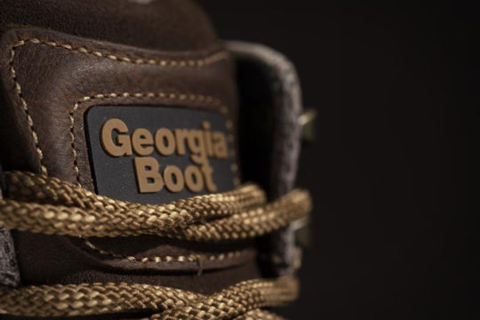 Close-up of a brown leather boot with 'Georgia Boot' label on a dark background